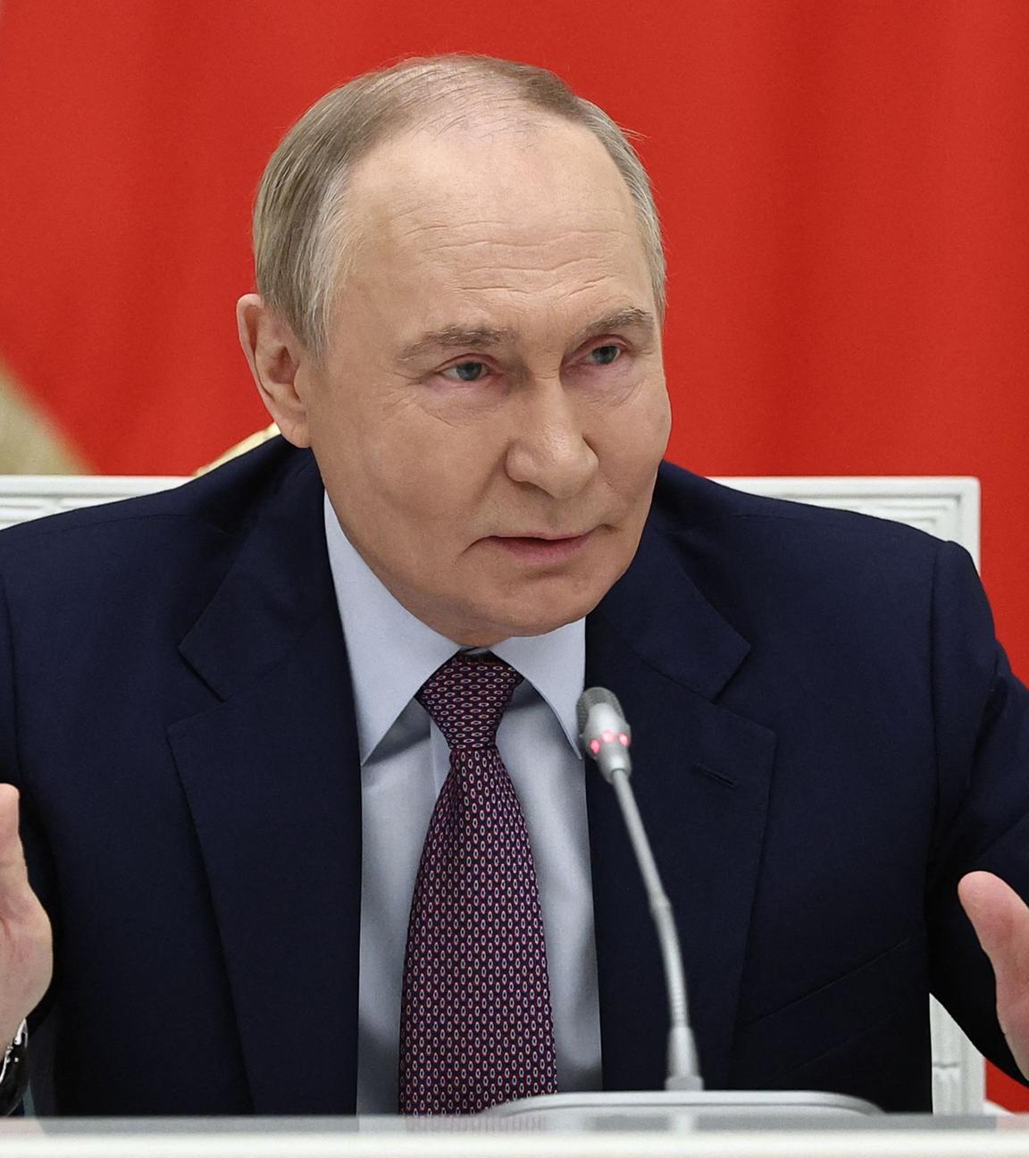 Putin hält vor einer russlandflagge eine Rede