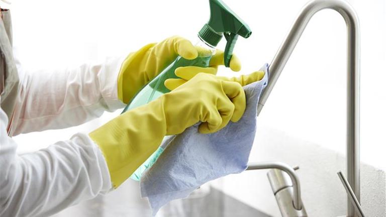 Bildausschnitt zeigt eine Hand, die eine Spüle reinigt