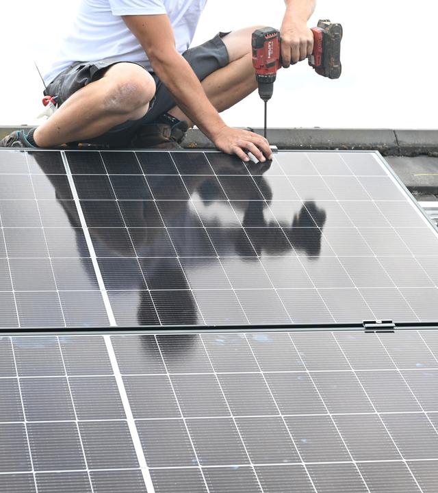 Auf einem Dach eines Privathauses wird eine PV Anlage zur Stromerzeugung installiert.