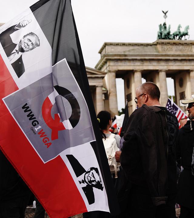 Archiv, Berlin: Auf einer schwarzweissroten Fahne, die ein Teilnehmer vor dem Brandenburger Tor hält, sind ein Bild von US Präsident Trump, der Buchstabe "Q" sowie der Schriftzug "WWG1WGA" (where we go one, we go all) aufgedruckt.