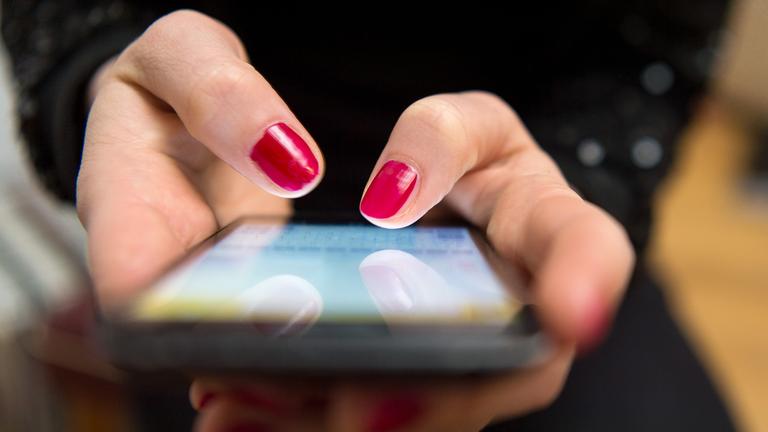 Eine Frau tippt auf einem Smartphone.