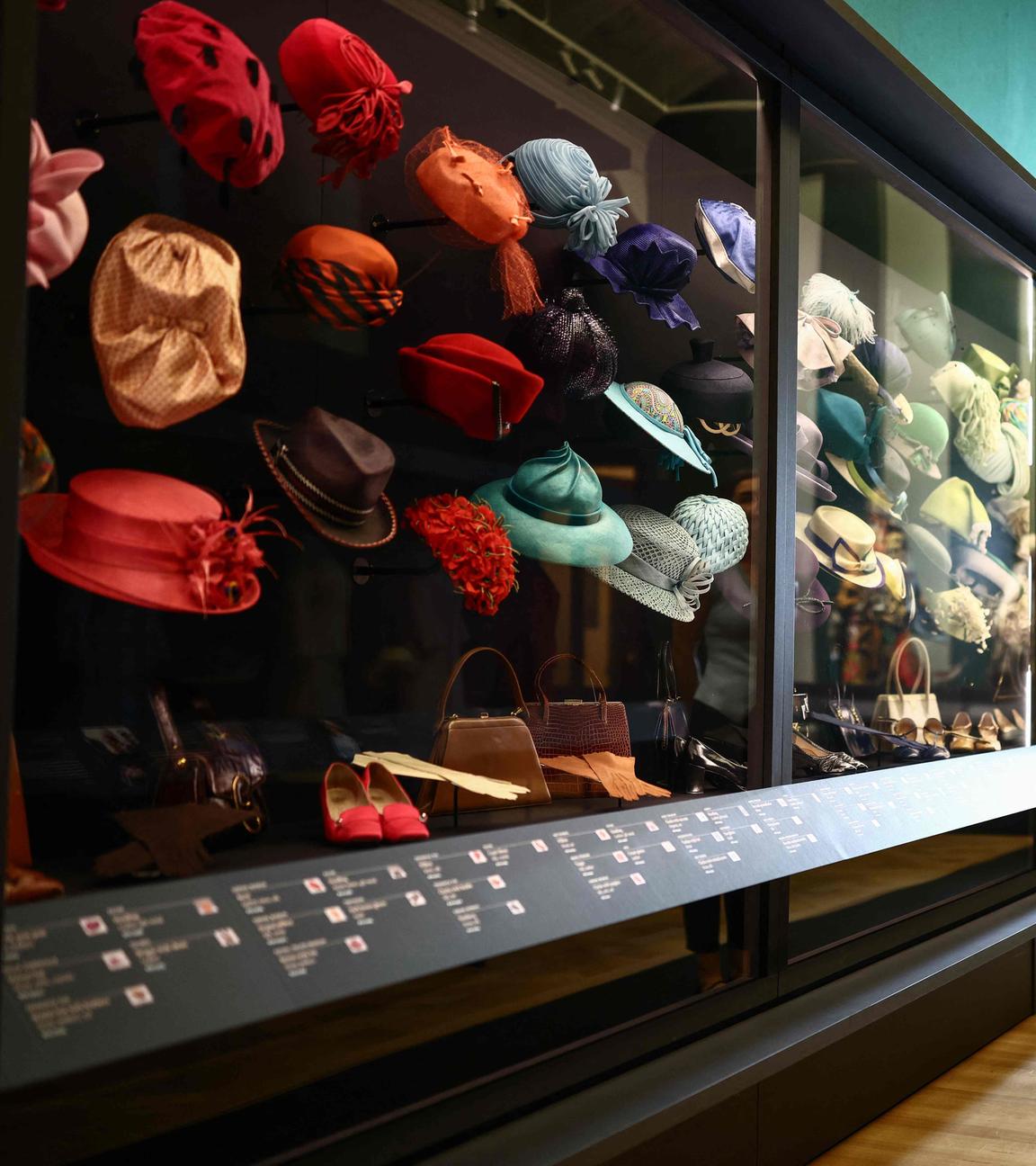 Ein Mitarbeiter neben einer Ausstellung verschiedener Hüte der Ausstellung „Queen Elizabeth II: Her Life in Style“ in der King’s Gallery im Buckingham Palace in London.