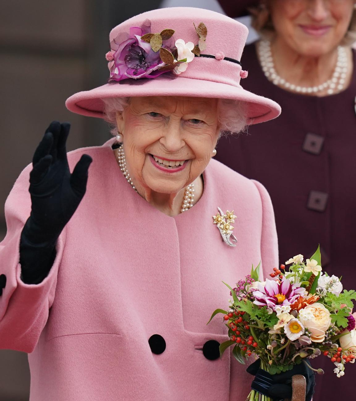  Großbritannien, Cardiff: Die britische Königin Elizabeth II. hält einen Blumenstrauß in der Hand und winkt, nachdem sie nach der Eröffnungszeremonie des walisischen Parlaments das Parlamentsgebäude verlässt.