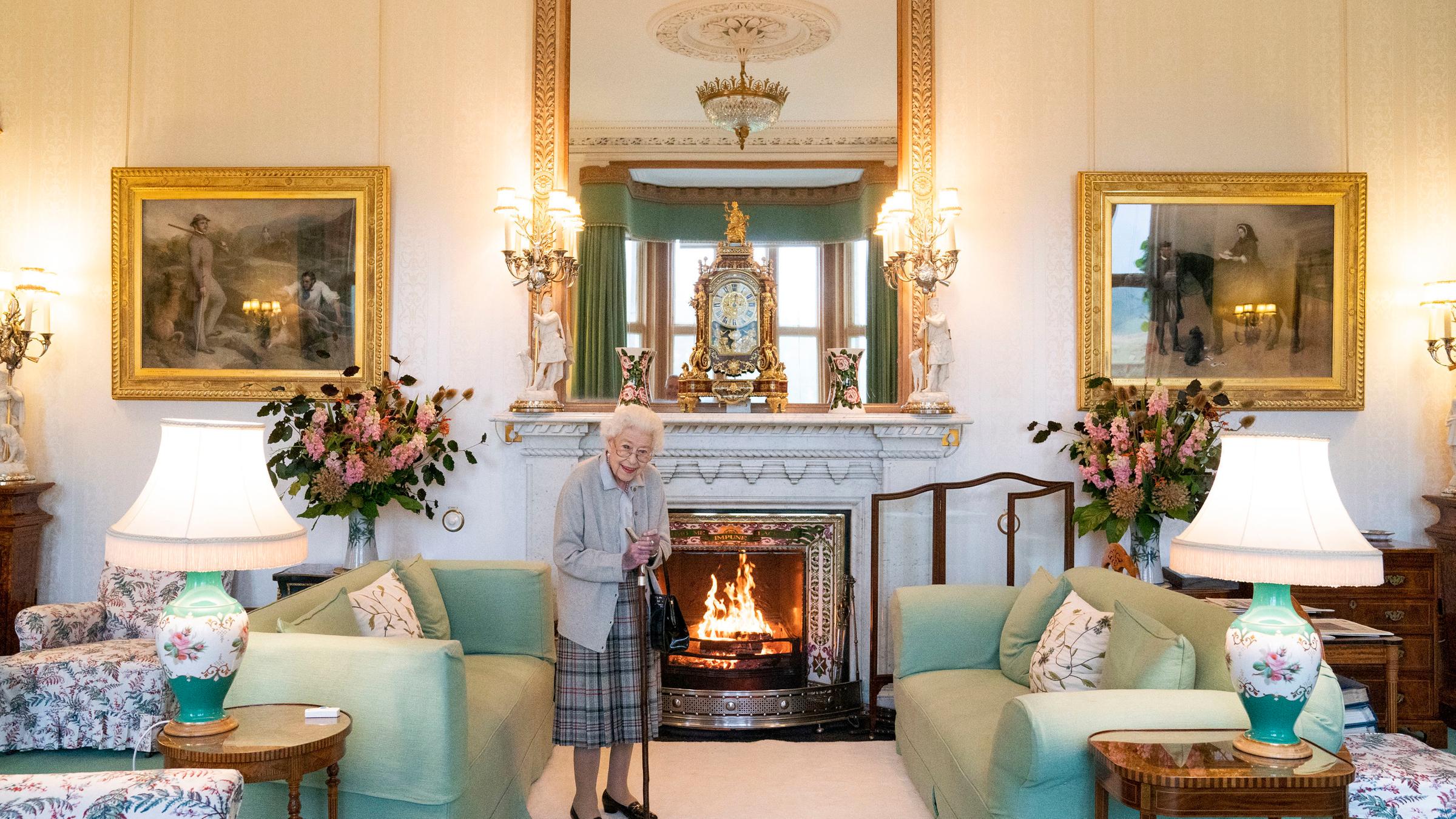 Queen Elizabeth steht im Drawing Room vor dem brennenden Kamin
