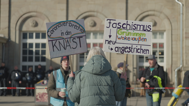 Demonstranten mit Plakaten auf einer Querdenker Demonstration.
