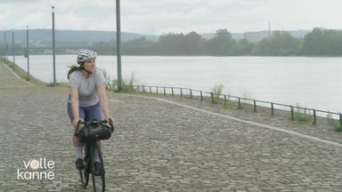 Frau sitzt auf ihrem Rennrad und fährt neben einem Fluss entlang