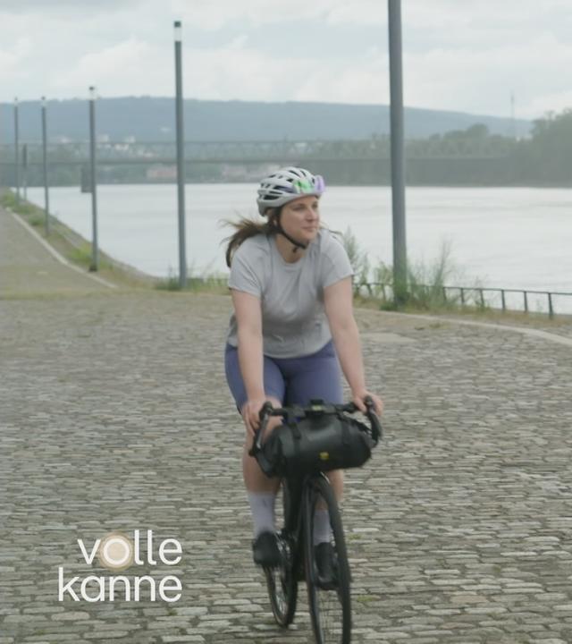 Frau sitzt auf ihrem Rennrad und fährt neben einem Fluss entlang