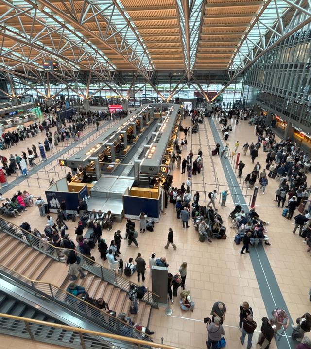 Zahlreiche Menschen stehen im Terminal des Hamburger Flughafens.