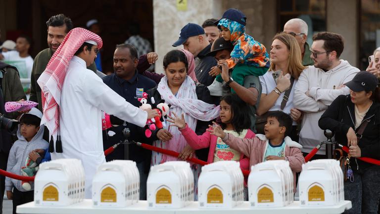 A volunteer distributes children's toys during Ramadan to people on the first day of the holy month of Ramadan, at Souq Waqif in Doha.