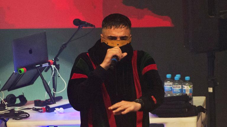 Rapper Haftbefehl performt vermumt auf einem Konzert.