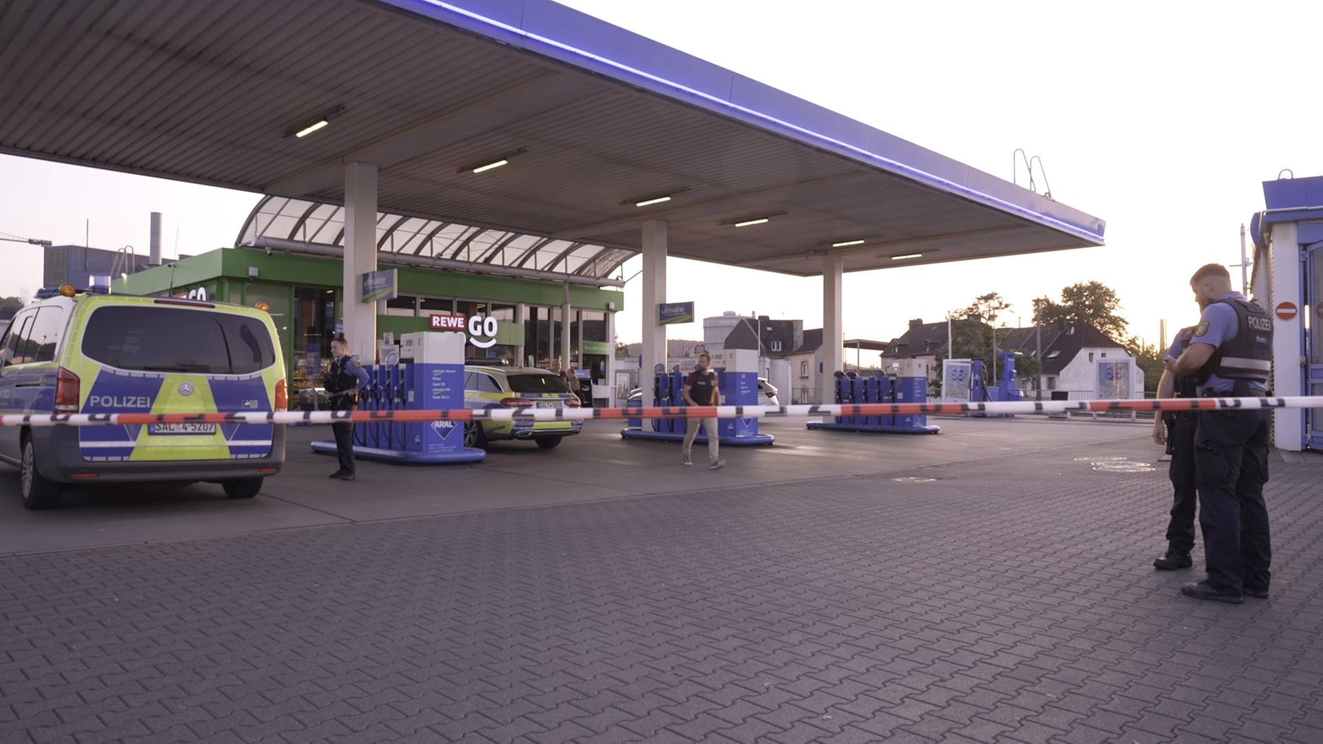 21.08.2025, Saarland, Völklingen: Polizeibeamte untersuchen den Tatort Tankstelle nach einem Raubüberfall.