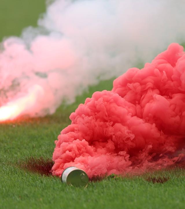 Rauchbomben am Boden des Fußballfeldes während Ausschreitungen beim DFB-Pokal am 21.08.2026.