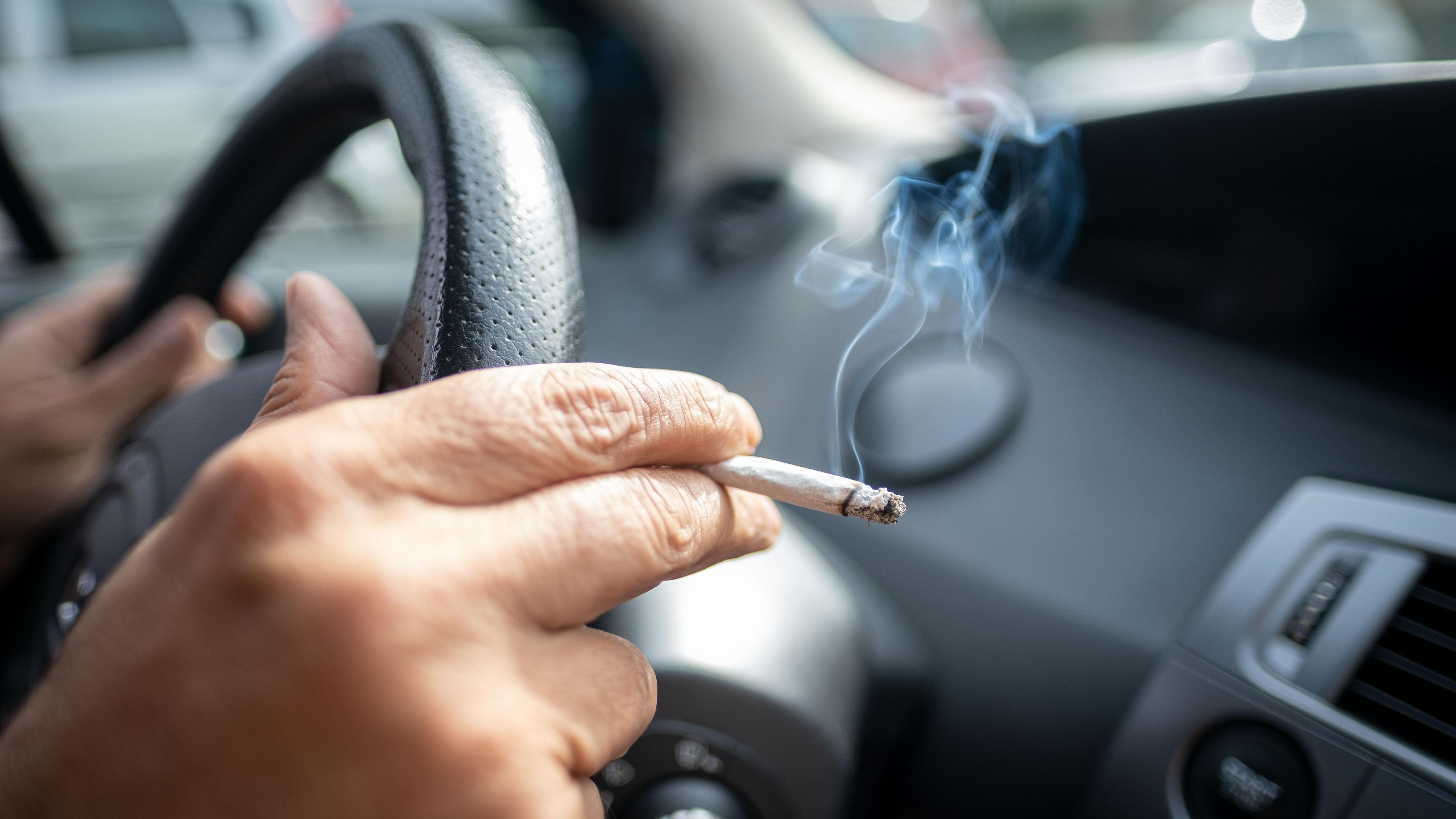 15.09.2019, Niedersachsen, Hannover: Ein Mann sitzt rauchend am Lenkrad eines Autos.