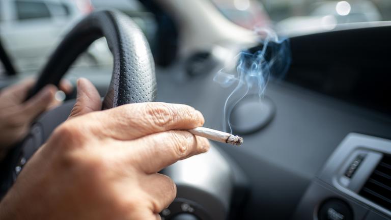 15.09.2019, Niedersachsen, Hannover: Ein Mann sitzt rauchend am Lenkrad eines Autos.