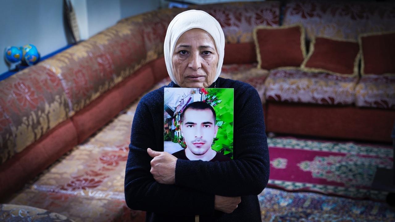 Rauda Hassan blickt in die Kamera und umklammert ein Bild ihres verschleppten Sohnes.
