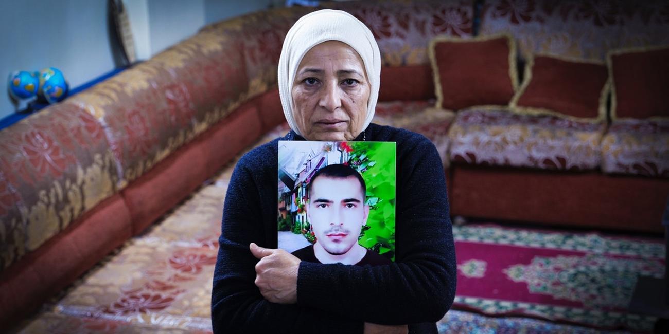 Rauda Hassan blickt in die Kamera und umklammert ein Bild ihres verschleppten Sohnes.