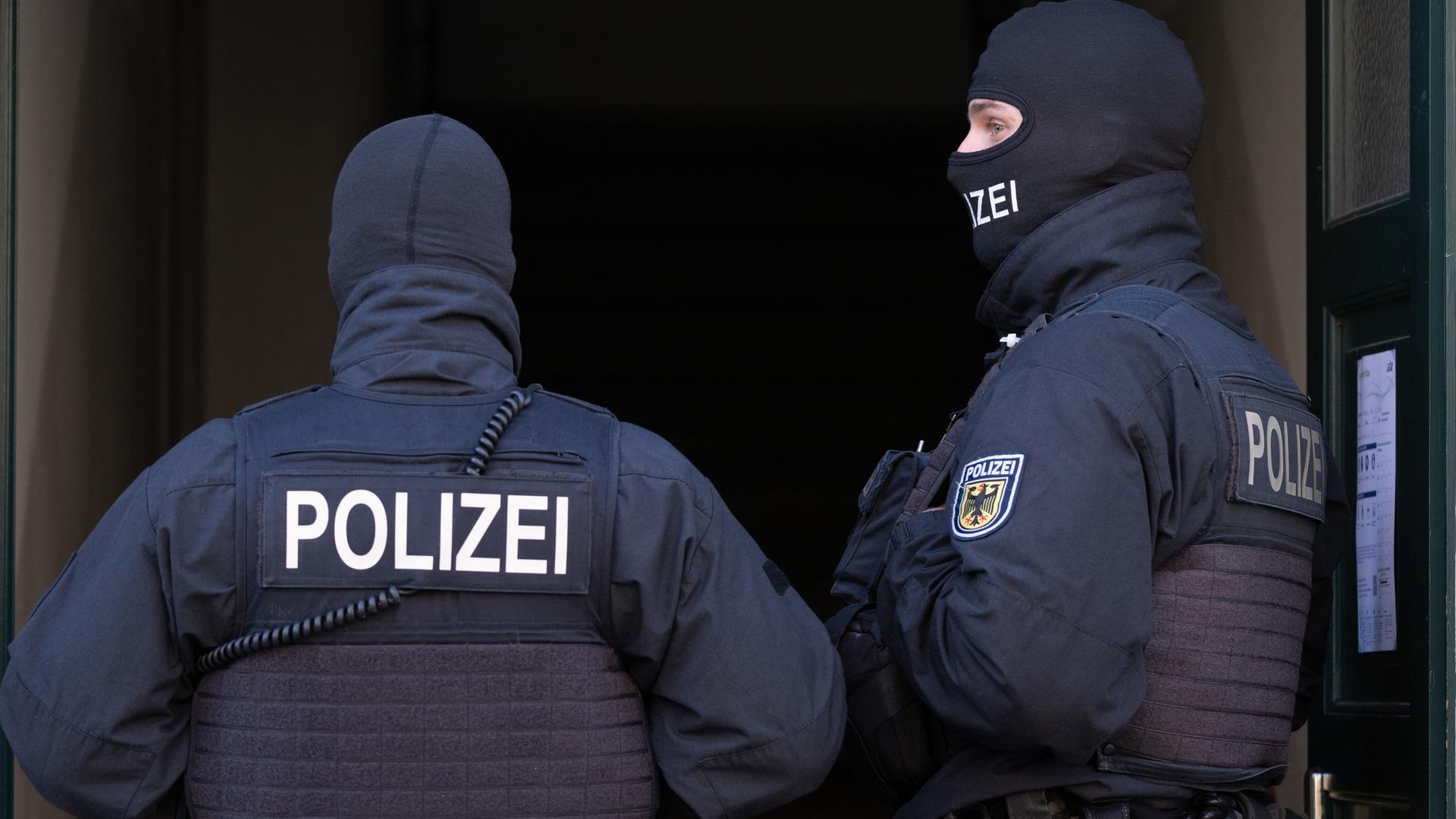 Symbolbild: Polizisten stehen während einer Razzia in einem Hauseingang