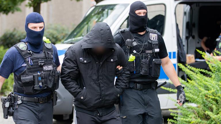 Ein Mann wird bei einem Polizeieinsatz abgeführt.