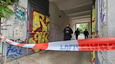 08.08.2024, Sachsen, Leipzig: In einem mit Flatterband abgesperrten Hauseingang gehen drei Polizisten.