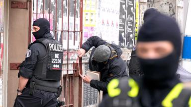 Polizeibeamte stehen in der Reichenberger Straße vor dem Buchladen Kalabalik. Ein halbes Jahr nach einem Brandanschlag auf die Stromversorgung des Berliner Technologieparks Adlershof hat die Polizei eine Razzia gegen Verdächtige gestartet.