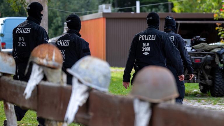 Mecklenburg-Vorpommern, Jamel: Polizisten gehen zur Sicherung von Beweismittel zum Haus des bundesweit bekannter Rechtsextremist Krüger auf dessen Gartenzaun rostige Stahlhelme hängen.