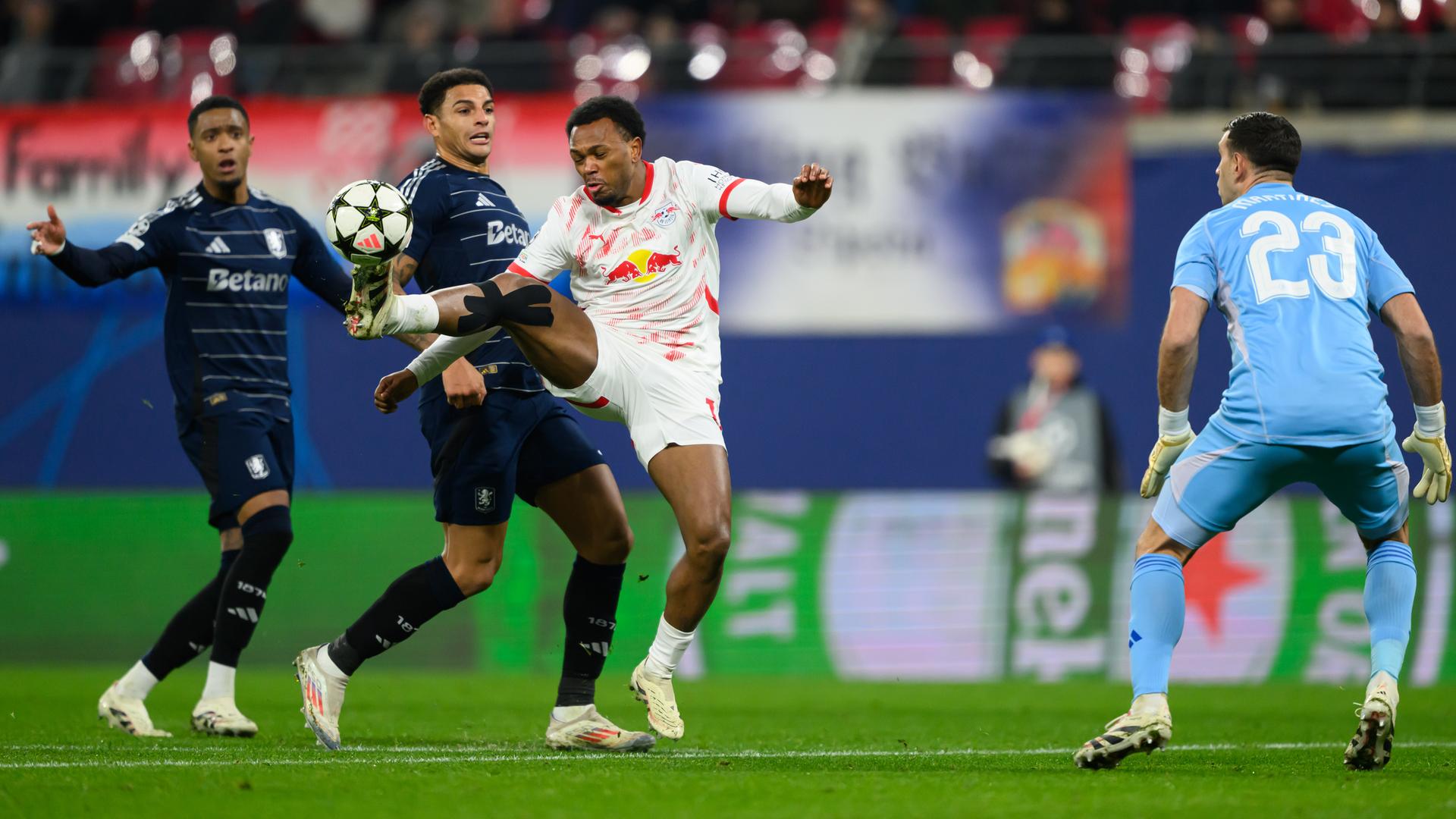 Fußball-Champions League, RB Leipzig - Aston Villa: Lois Openda (3.v.l.) staubt gegen Ezri Konsa (l.), Diego Carlos (2.v.l.) und Torwart Emiliano Martinez ab und macht sich auf den Weg, das Tor zum 1:1 zu erzielen.