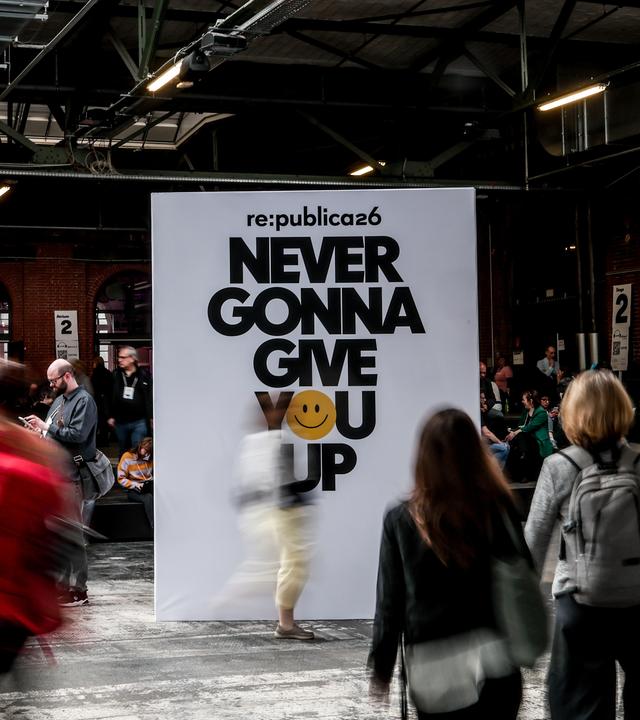 Besucher in einer Halle bei der re:publica. In der Mitte eine Tafel mit dem diesjährigen Mottospruch.
