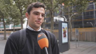 Zu sehen ist ein junger Mann in der Stadt, der interviewed wird