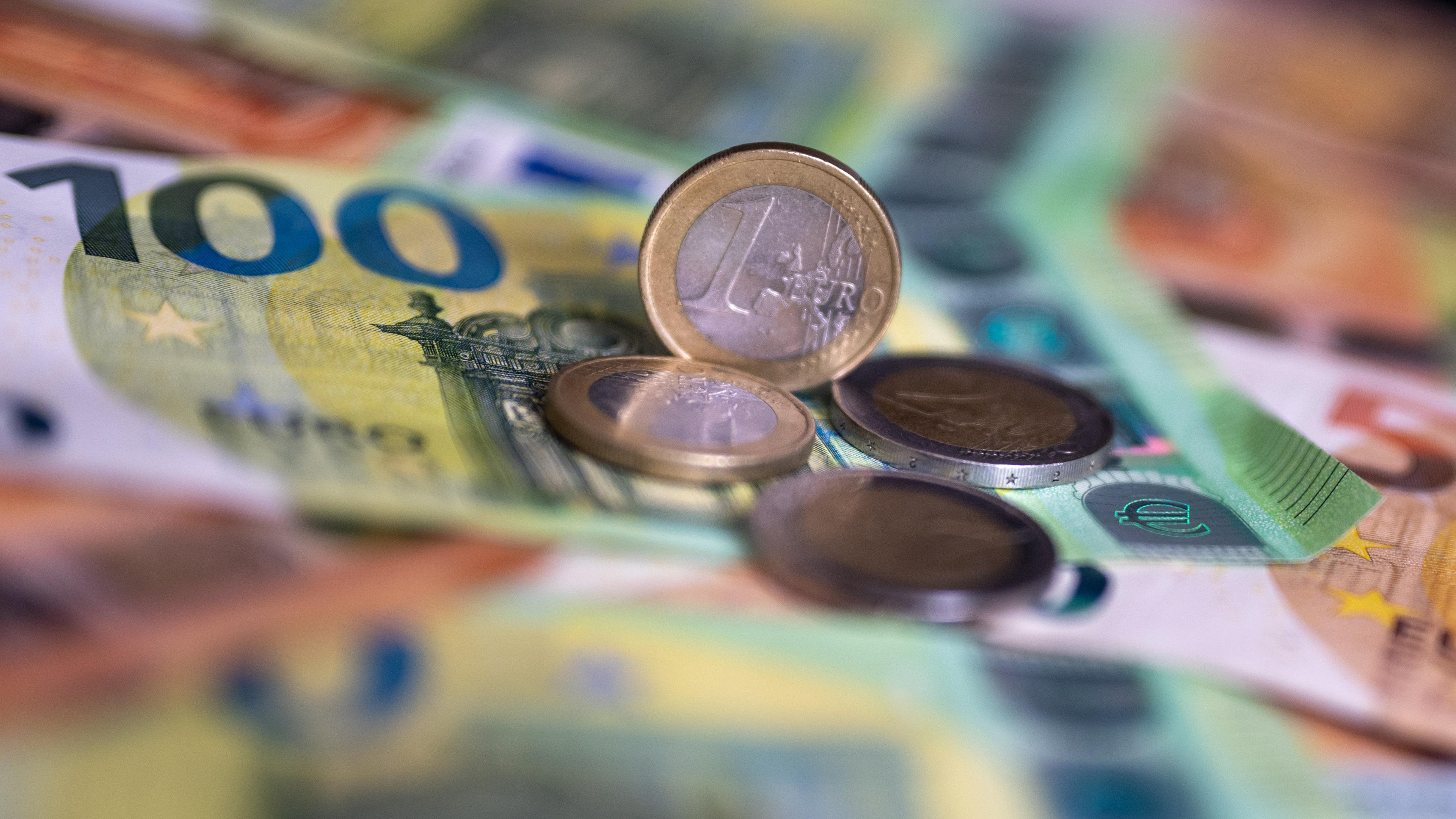 Berlin: Geldscheine mit dem Wert von 100 und 50 Euro und Münzen liegen auf einem Tisch.