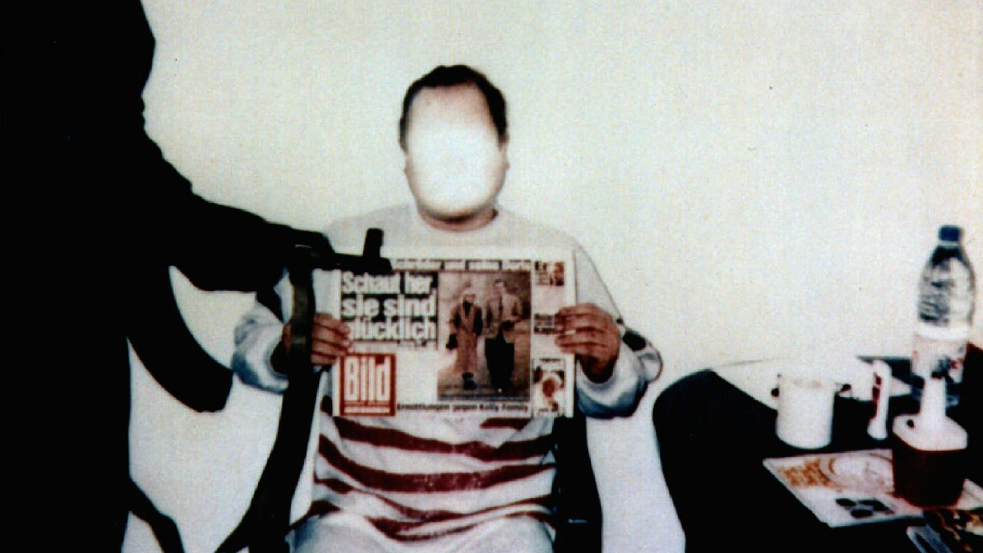 Jan Philipp Reemtsma sitzt auf einem Stuhl und hält die Ausgabe der Bild-Zeitung vom 26. März 1996 in die Kamera.