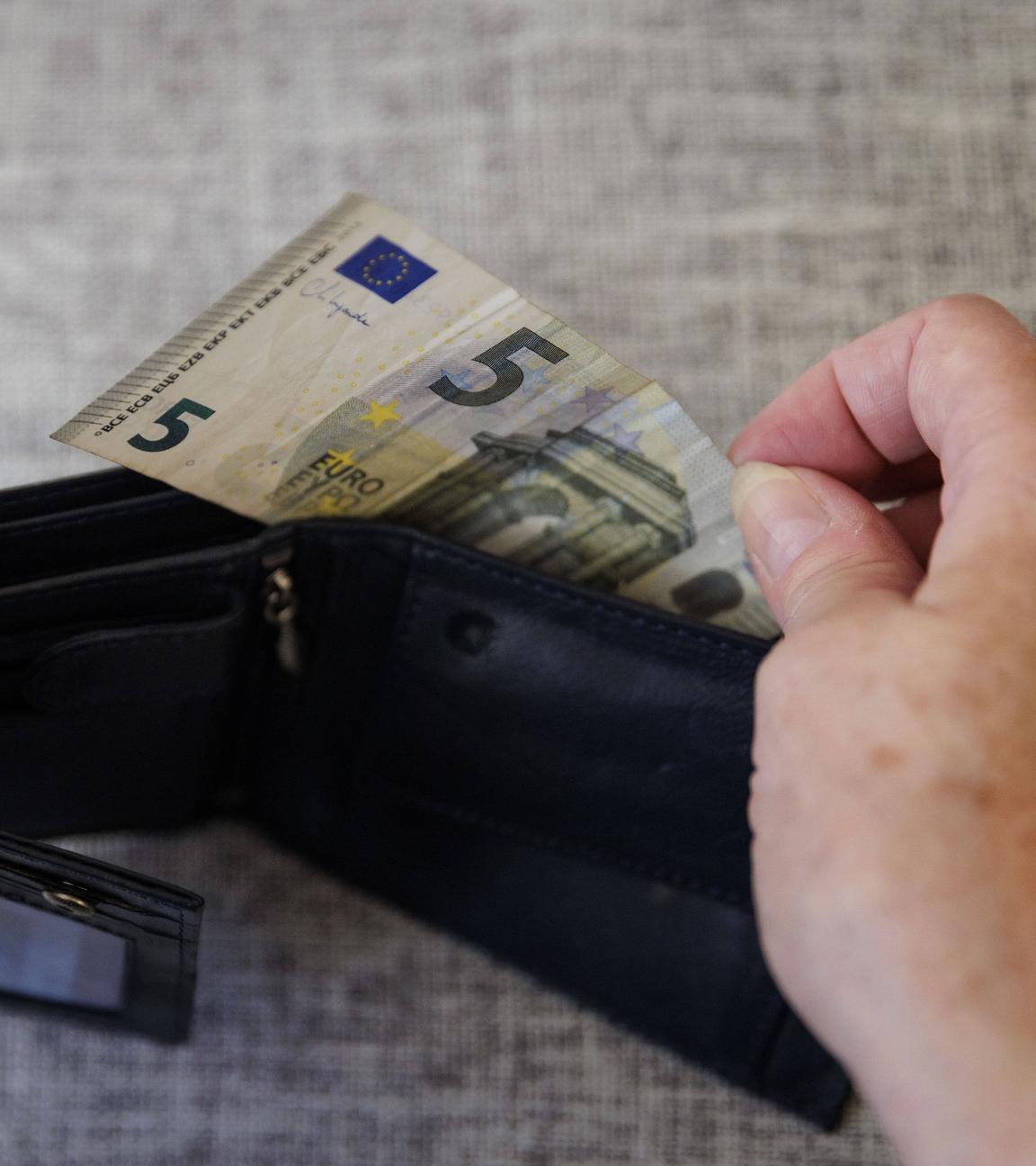 Eine ältere Frau nimmt fünf Euro aus einem Portemonnaie am 05.08.2024 in Berlin.
