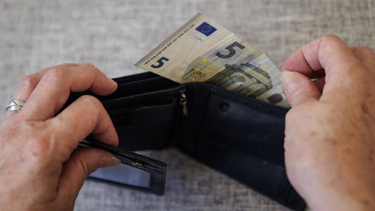 Eine ältere Frau nimmt fünf Euro aus einem Portemonnaie am 05.08.2024 in Berlin.