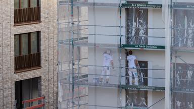 Arbeiter verputzen ein Haus mit Eigentumswohnungen.
