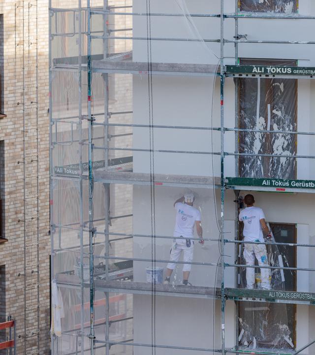 Arbeiter verputzen ein Haus mit Eigentumswohnungen.