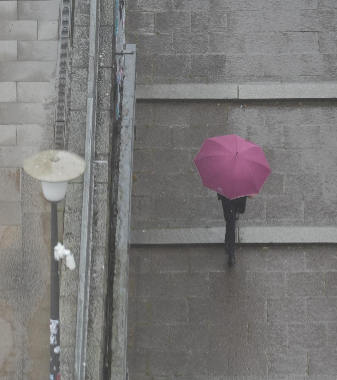 Passanten gehen mit Regenschirmen im strömenden Regen durch die Innenstadt.