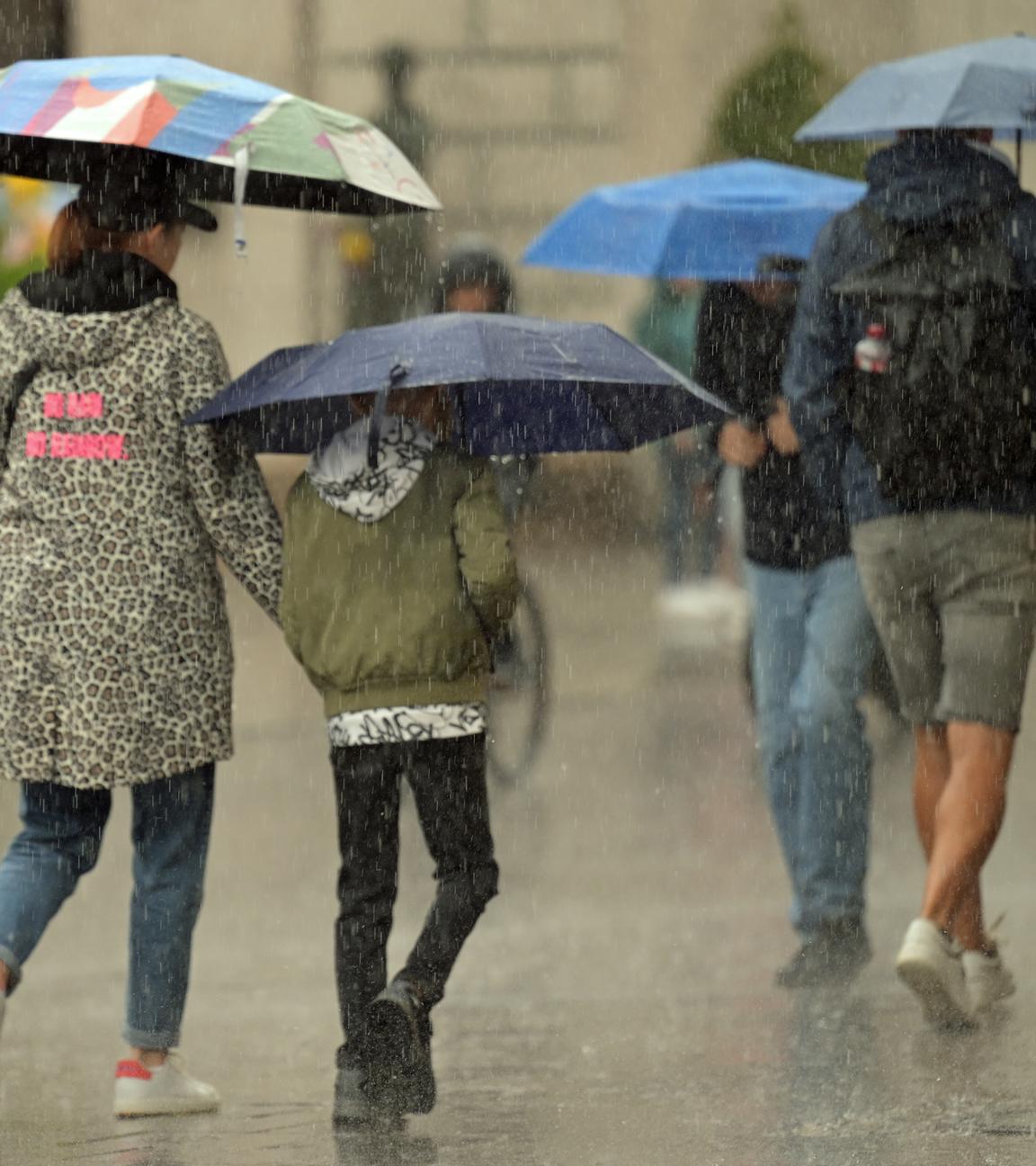 Bayern, München: Passanten gehen mit Regenschirmen durch die Altstadt.