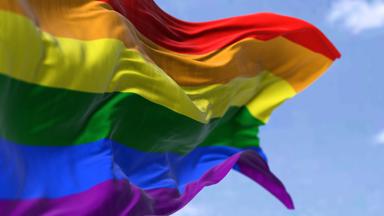 Symbolbild: die Regenbogenflagge, die an einem klaren Tag im Wind weht