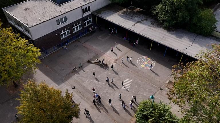 Ein Schulhof von oben mit Kindern und einem Schulgebäude