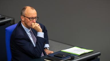 Der Bundeskanzler Friedrich Merz ist zu sehen im Bundestag. Er sitzt und schaut nachdenklich.