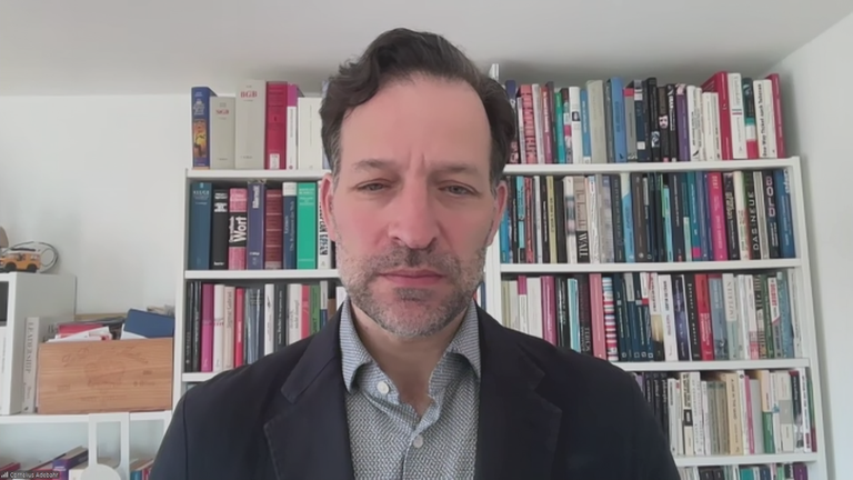 Cornelius Adebahr vor einem Bücherregal.