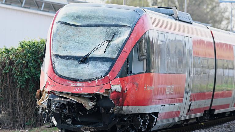 Ein Regionalzug mit beschädigter Front steht am Bahnhof auf den Gleisen. 