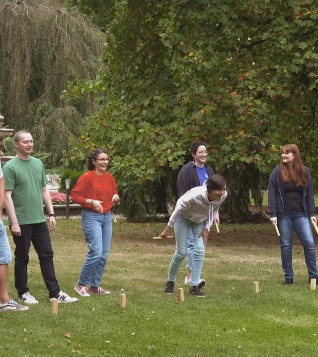 Reha für junge Krebspatienten: Junge Menschen zusammen auf einer Wiese bei einem Spiel.