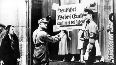 SA Männer kleben Plakate an Geschäfte mit der Aufschrift: "Deutsche wehrt euch! Kauft nicht bei Juden!"
