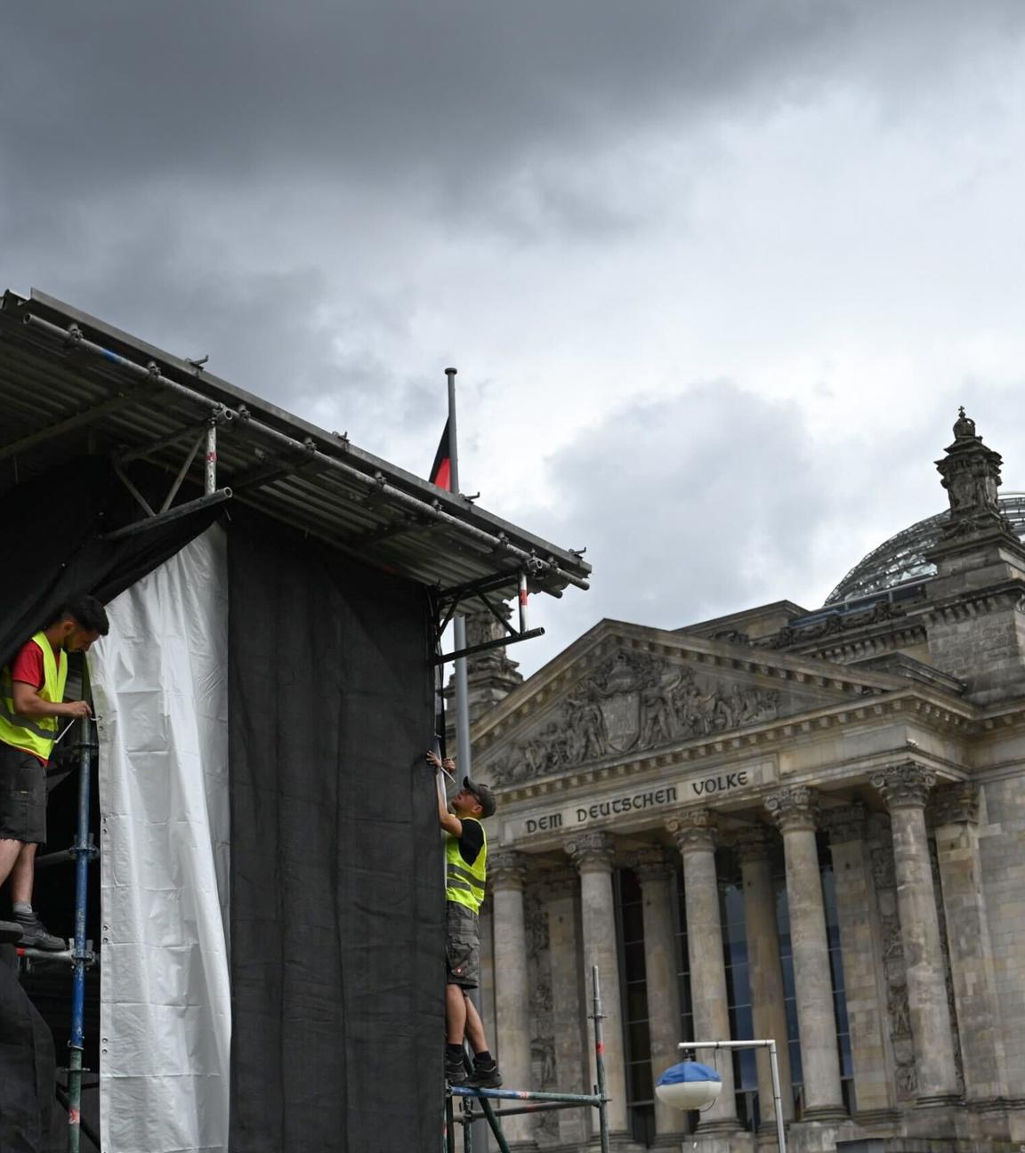 Zwei Arbeiter richten eine Plane auf einem Gerüst zur Vorbereitung einer Projektion anlässlich des 30. Jahrestags der Reichstag-Verhüllung.