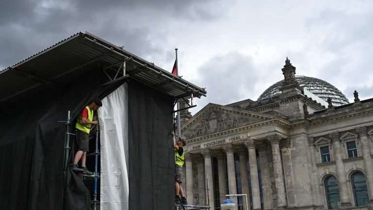 Zwei Arbeiter richten eine Plane auf einem Gerüst zur Vorbereitung einer Projektion anlässlich des 30. Jahrestags der Reichstag-Verhüllung.