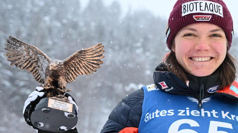 Agnes Reisch hält die Trophäe für ihren dritten Platz beim Skispringen in Villach in der rechten Hand.