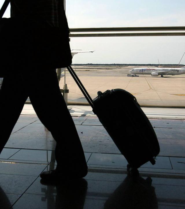 schatten eines reisenden mannes mit rollkoffer am flughafen