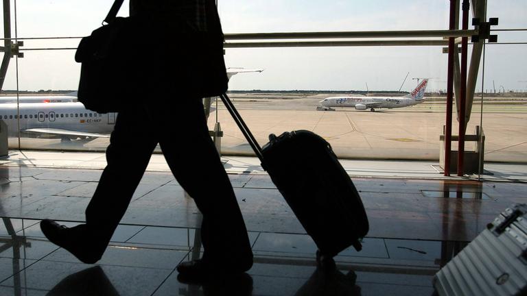 schatten eines reisenden mannes mit rollkoffer am flughafen