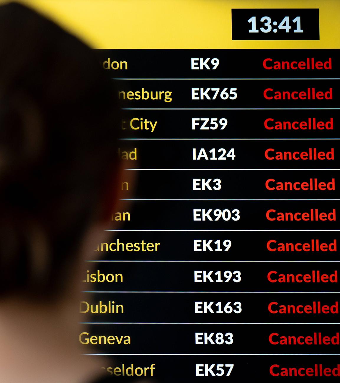 Eine Frau steht vor der Anzeigetafel an einem Flughafen.