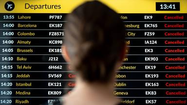 Eine Frau steht vor der Anzeigetafel an einem Flughafen.